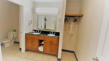 Un baño con tocador de madera, dos lavamanos, un espejo y un inodoro.