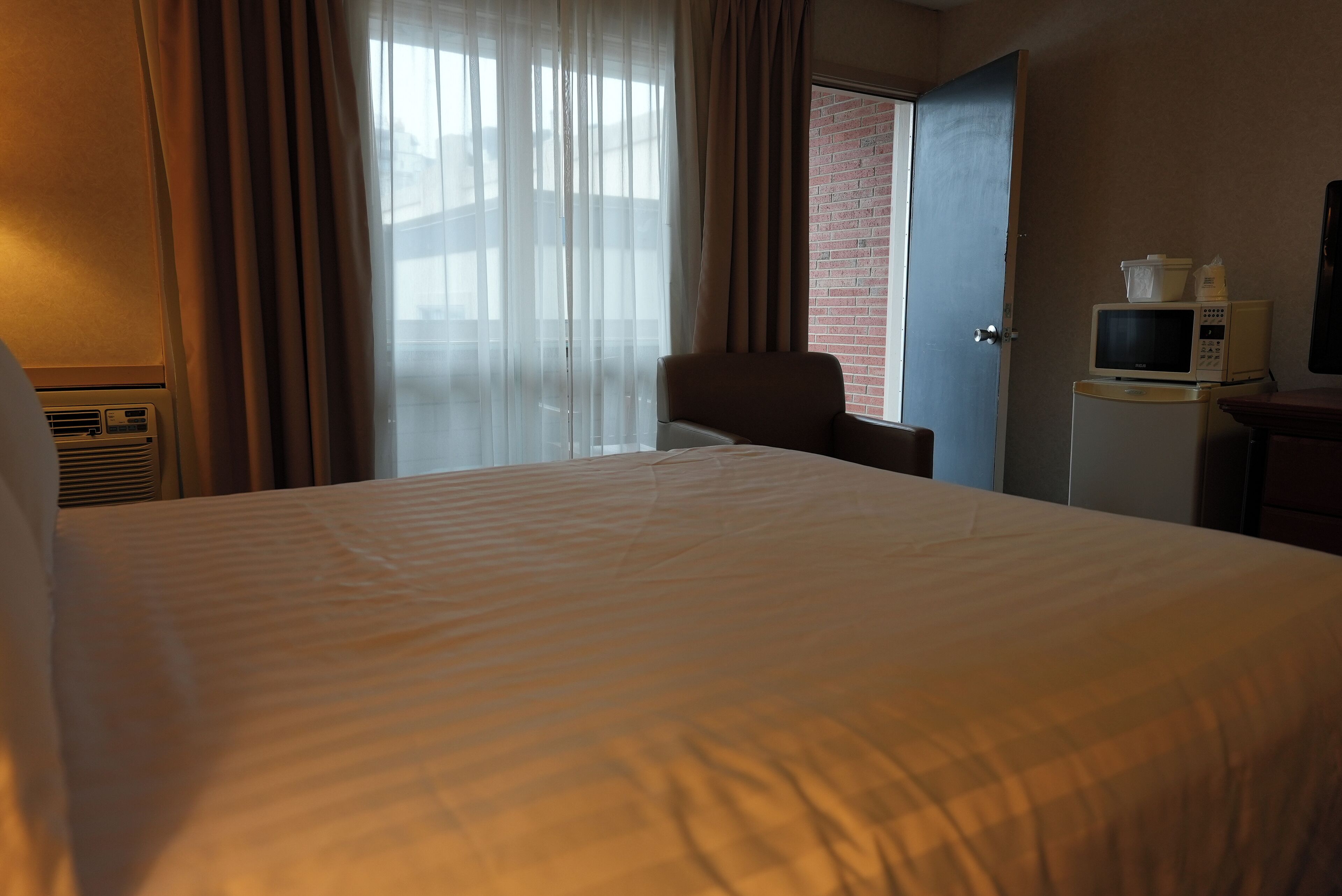 Ein Hotelzimmer mit einem großen Bett, einem Sessel, einem Fernseher und einer Mikrowelle auf einem kleinen Tisch.