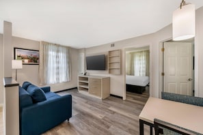 Een moderne hotelkamer met een bank, televisie, bureau en een bed.