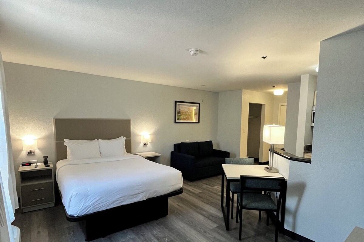 Een hotelkamer met een bed, nachtkastjes, een bureau en een stoel.