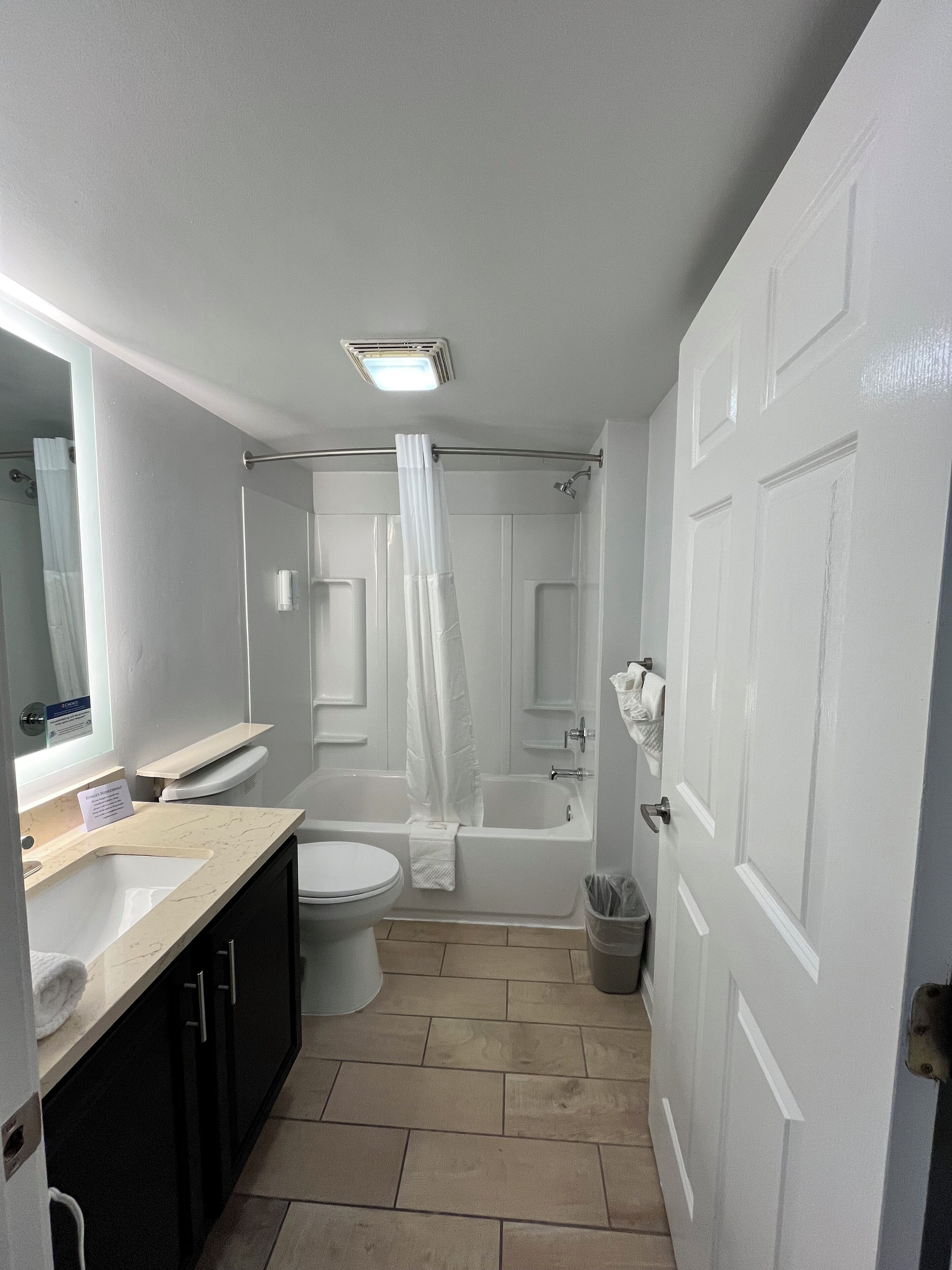 A modern bathroom with a toilet, sink, bathtub, and shower curtain.