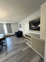 Una habitación moderna con cama, escritorio, silla, televisor y armario.