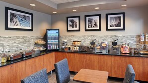 Un café moderno con un mostrador que exhibe pasteles y máquinas de café, fotografías enmarcadas en la pared y zona de estar.