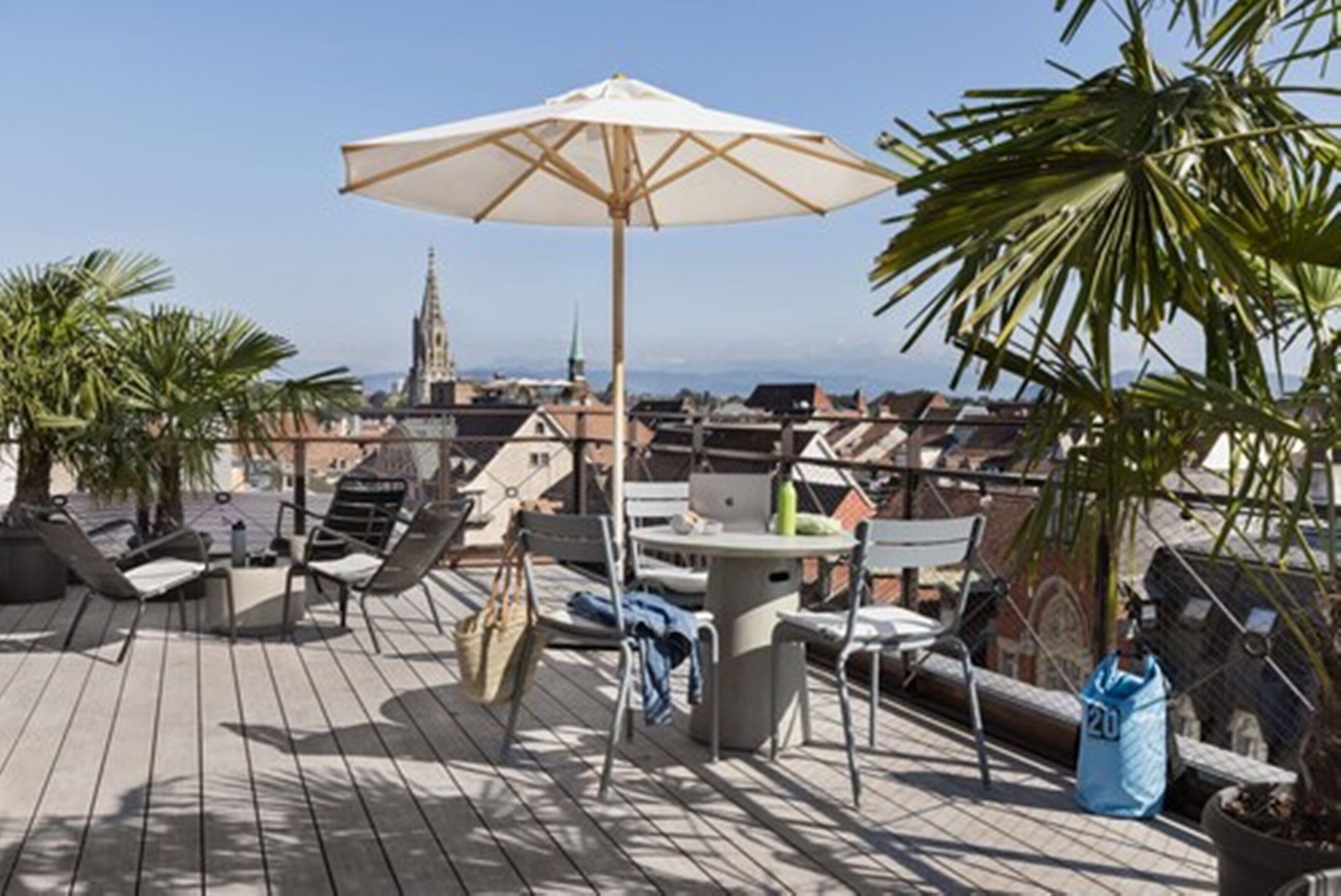 A rooftop terrace with outdoor seating, a table, and an umbrella.