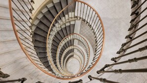 A spiral staircase with a wooden handrail and metal balusters, leading to an upper floor. - Stay KooooK Bern City – Online Check In (Bern)