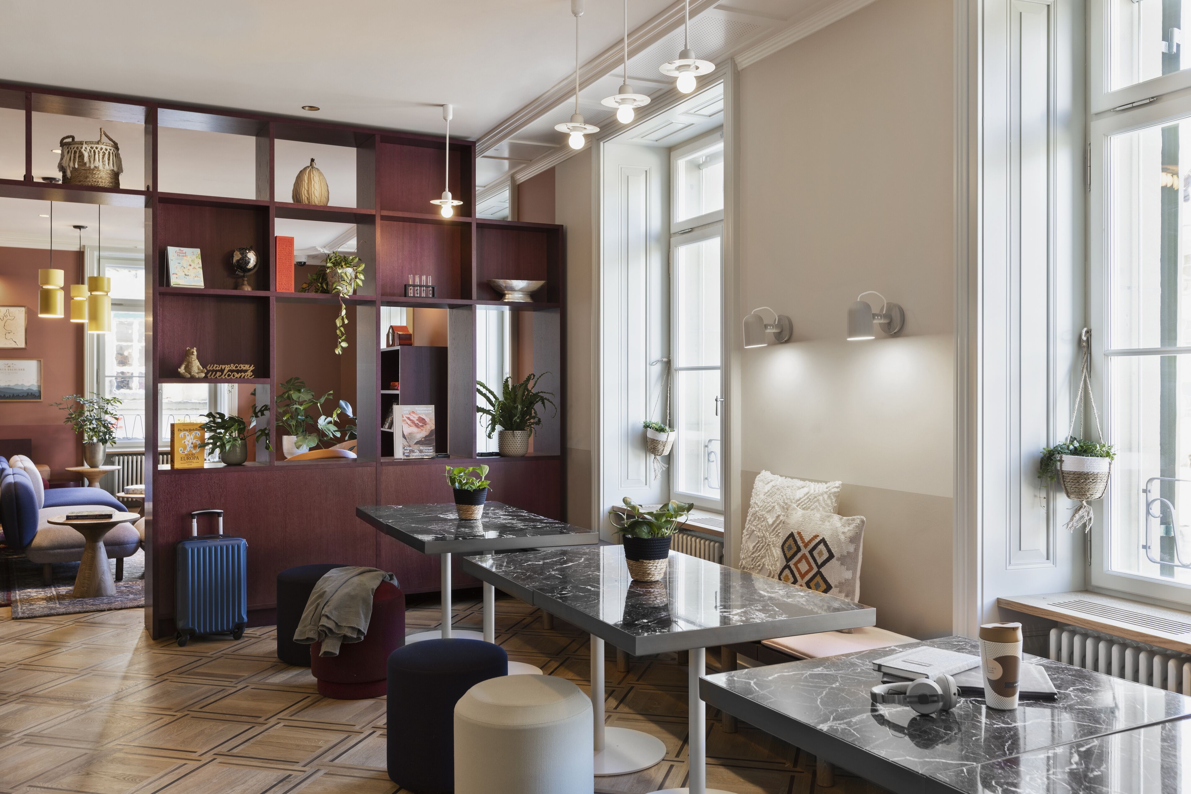 A modern living room with a marble table, comfortable seating, a bookshelf, and large windows.