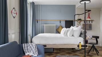 Une chambre moderne avec un lit, un canapé, un bureau et une lampe sur pied.