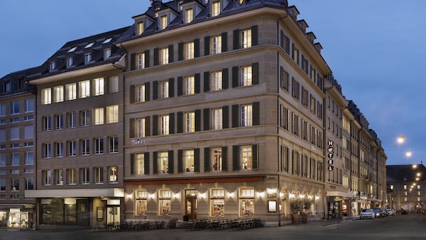 A multi-story hotel with a classic European architectural style, featuring a prominent entrance with outdoor seating and a visible sign indicating it is a hotel. - Stay KooooK Bern City – Online Check In (Bern)