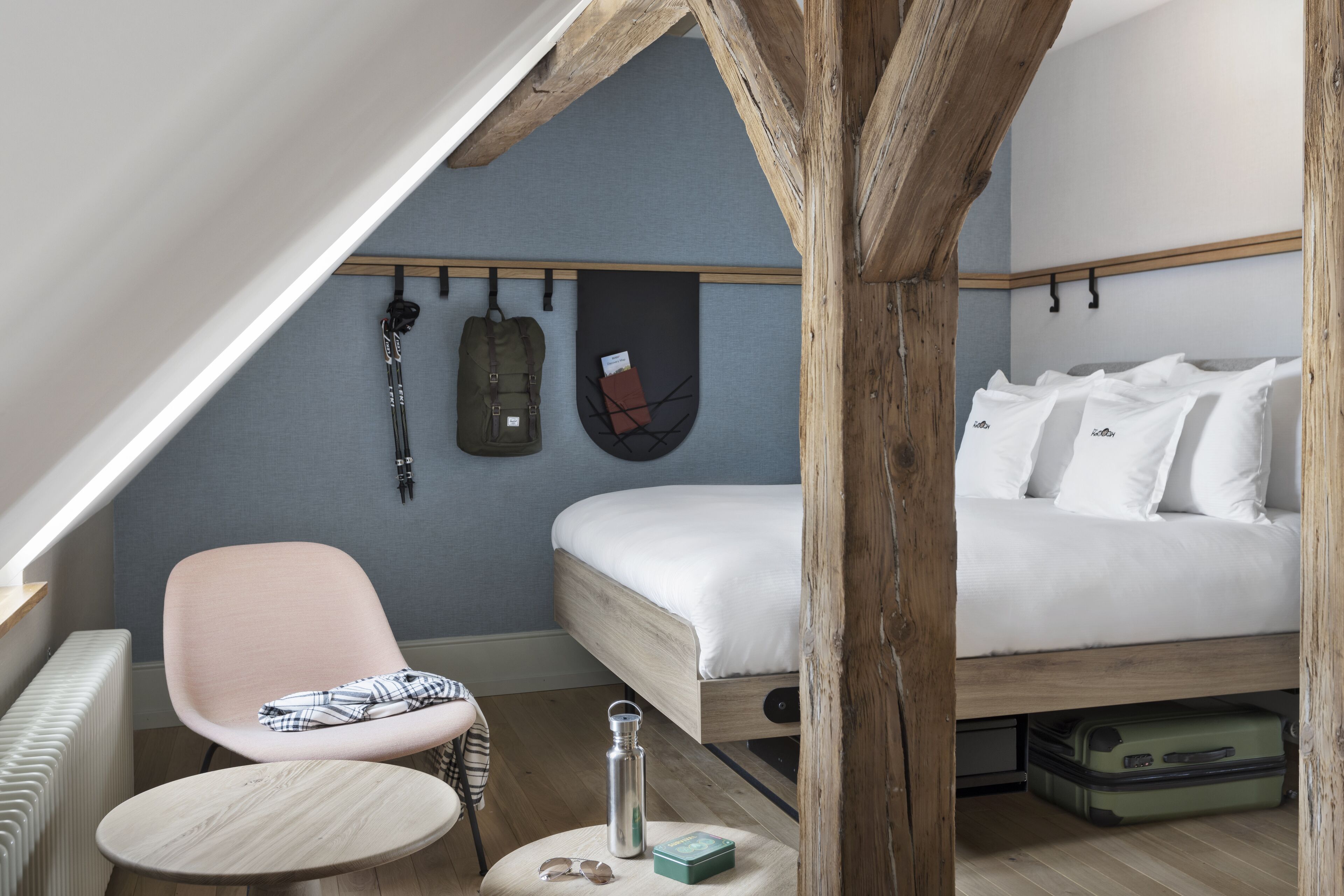 Une chambre à coucher de taille réduite, avec un lit en mezzanine, une chaise, une petite table et un radiateur.