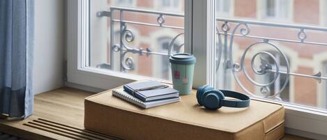A window seat with a cushioned bench, a notebook, a cup, and headphones.