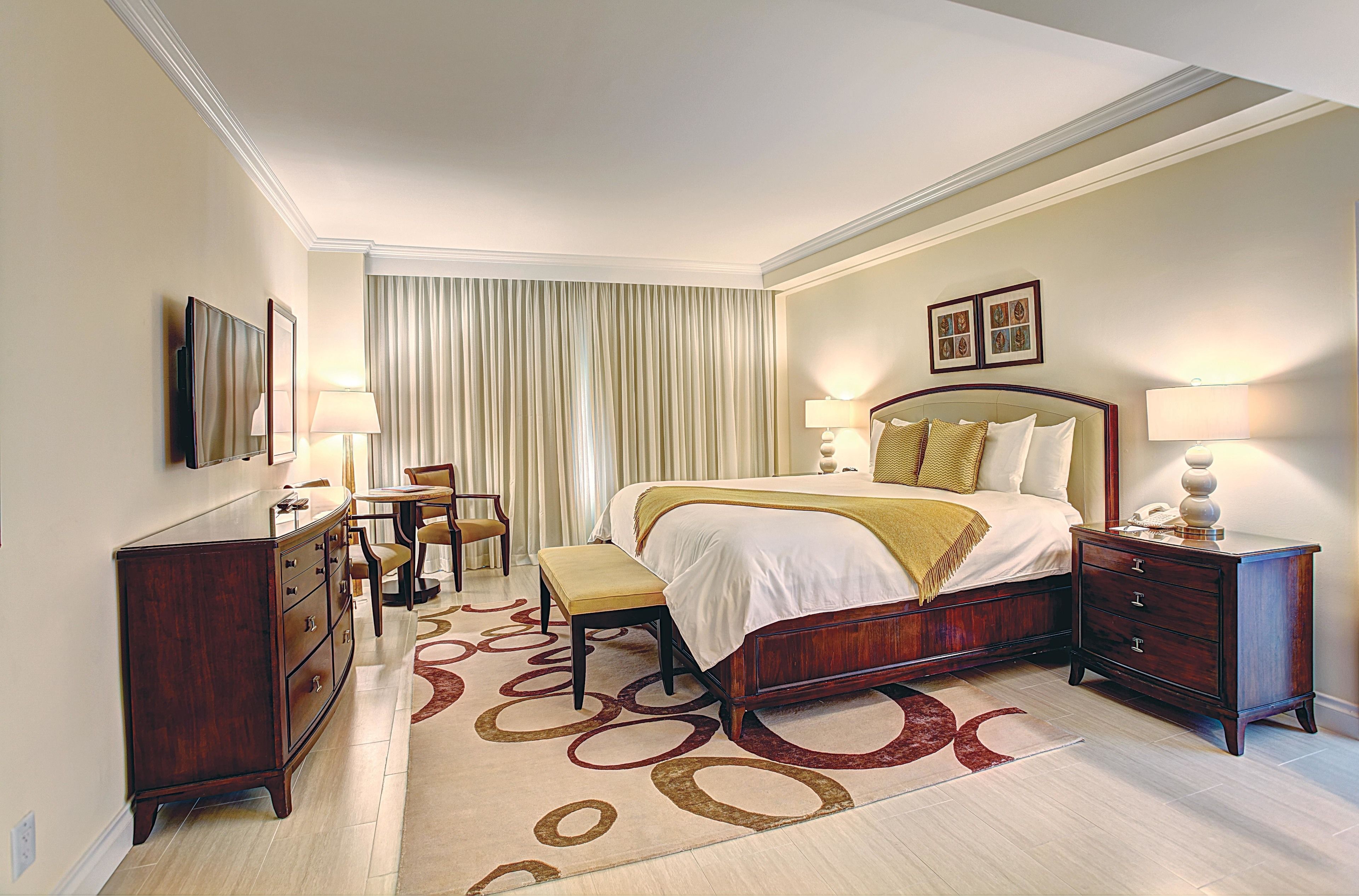 A hotel room with a large bed, bedside tables, a desk, and a chair.