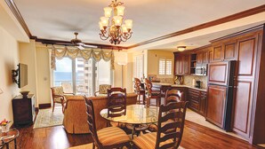 A spacious kitchen with wooden cabinets, a dining area with a glass table, and a view of the ocean through large windows. - Sea View Hotel, Bal Harbour, On The Ocean (Bal Harbour)