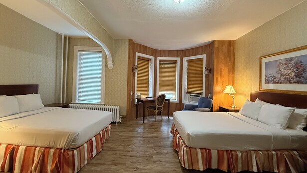A hotel room with two beds, a desk, and a chair. - Windsor Inn Hotel (Washington)