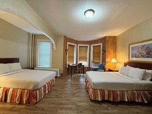Une chambre d’hôtel avec deux lits, un bureau et une chaise.