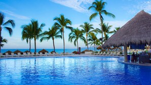 A poolside area with lounge chairs and palm trees, overlooking a body of water. - Marival Emotions All-Inclusive Resort by Mercure (Nuevo Nayarit)