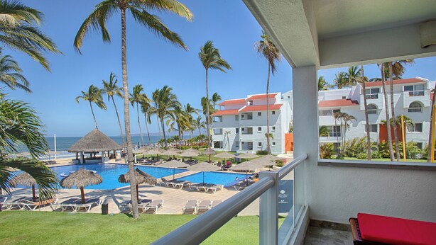 A hotel balcony with a pool, palm trees, and a view of the ocean. - Marival Emotions All-Inclusive Resort by Mercure (Nuevo Nayarit)