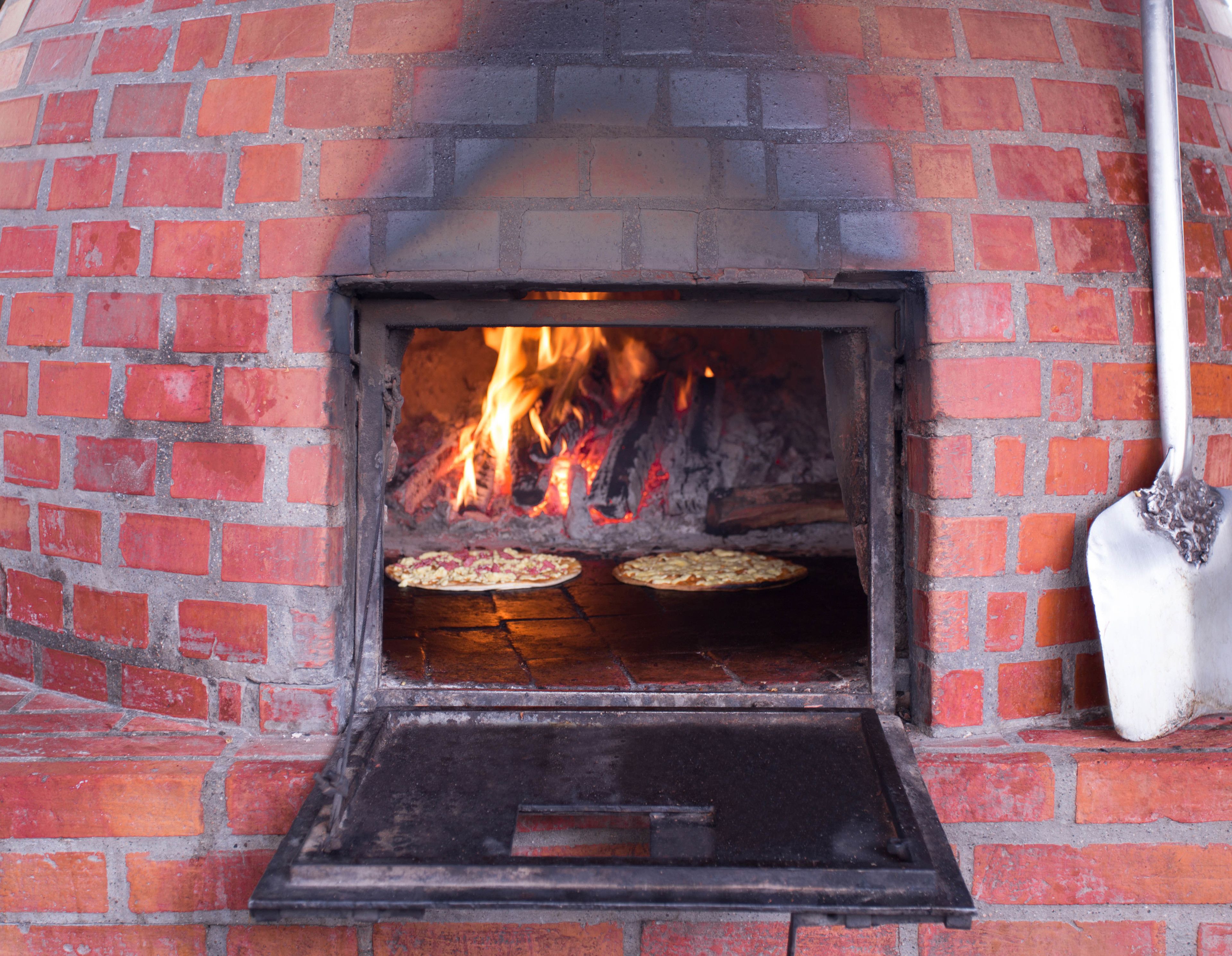 A brick oven pizza oven with two pizzas being cooked.