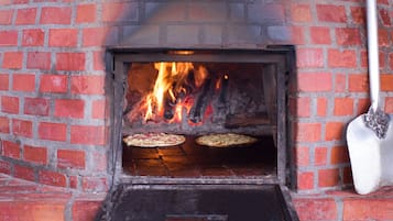 A brick oven pizza oven with two pizzas being cooked.
