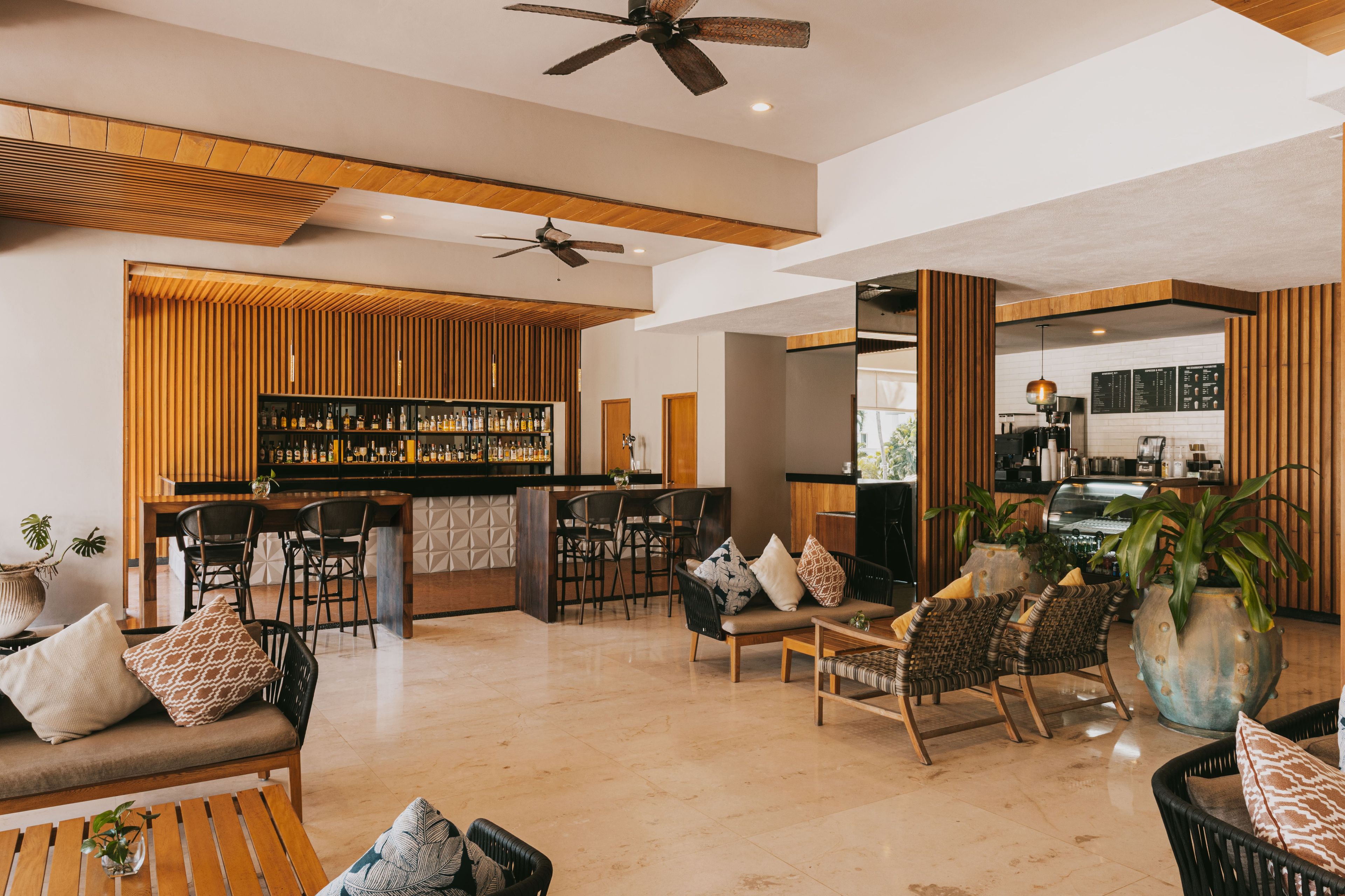 Un amplio salón con barra, diferentes disposiciones de asientos y una cocina visible al fondo.