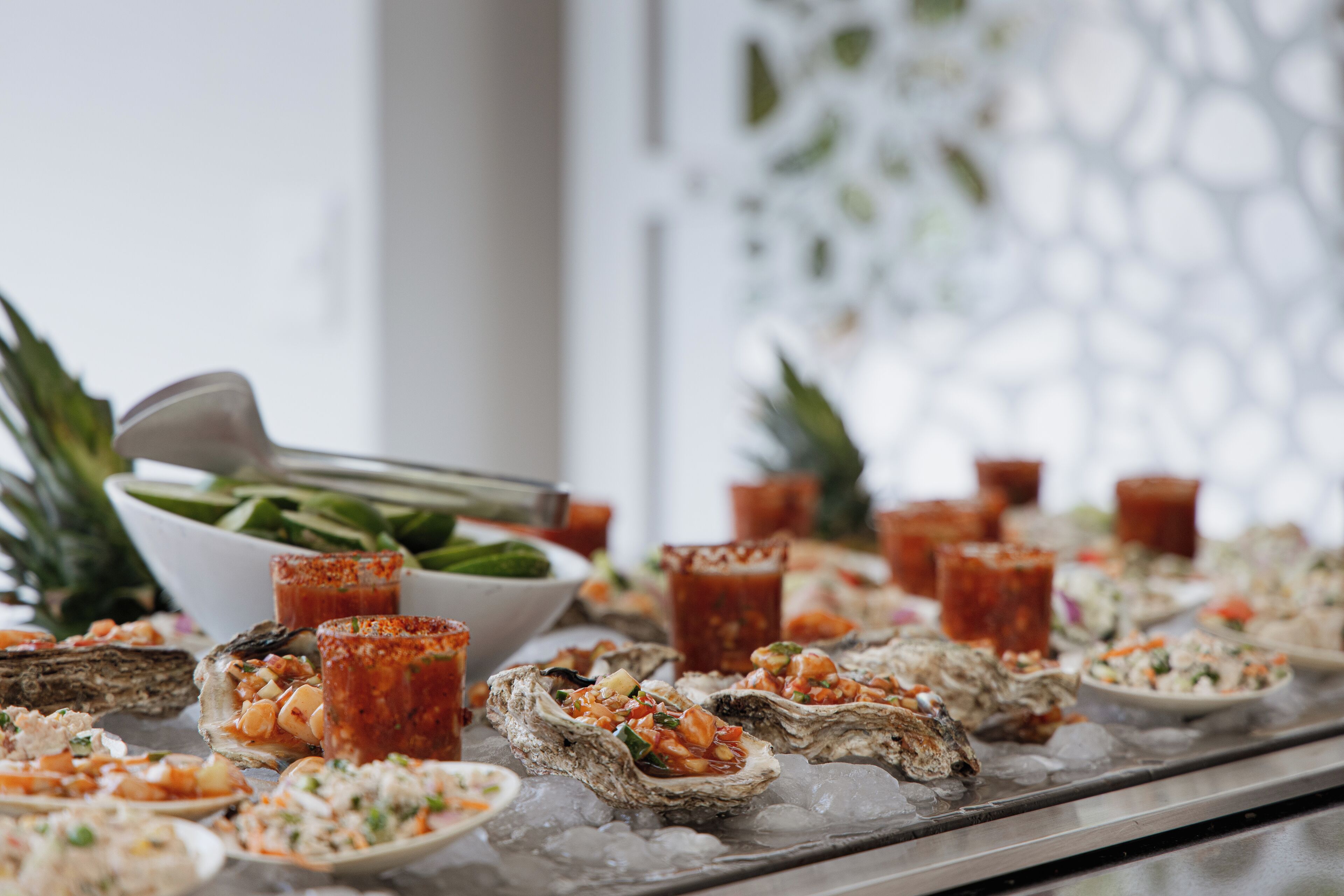 A seafood buffet with oysters on ice, various salads, and tropical fruits.