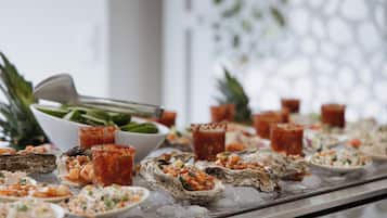 A seafood buffet with oysters on ice, various salads, and tropical fruits.