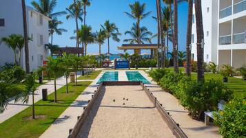 A pool area with a sandy floor, surrounded by palm trees and a building with a sign reading "MARIAH".
