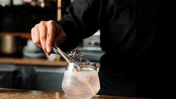 A person pouring a drink into a glass with a floral garnish.
