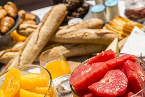 Variedad de alimentos para el desayuno, incluyendo pan, naranjas y pomelos.