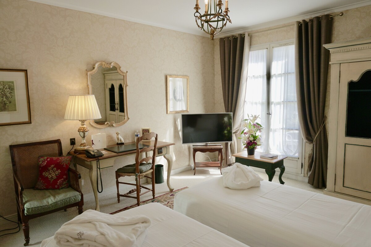 Une chambre d’hôtel équipée d’un lit, d  ’un bureau, d’une chaise, d’une télévision et d’une fenêtre avec des rideaux.
