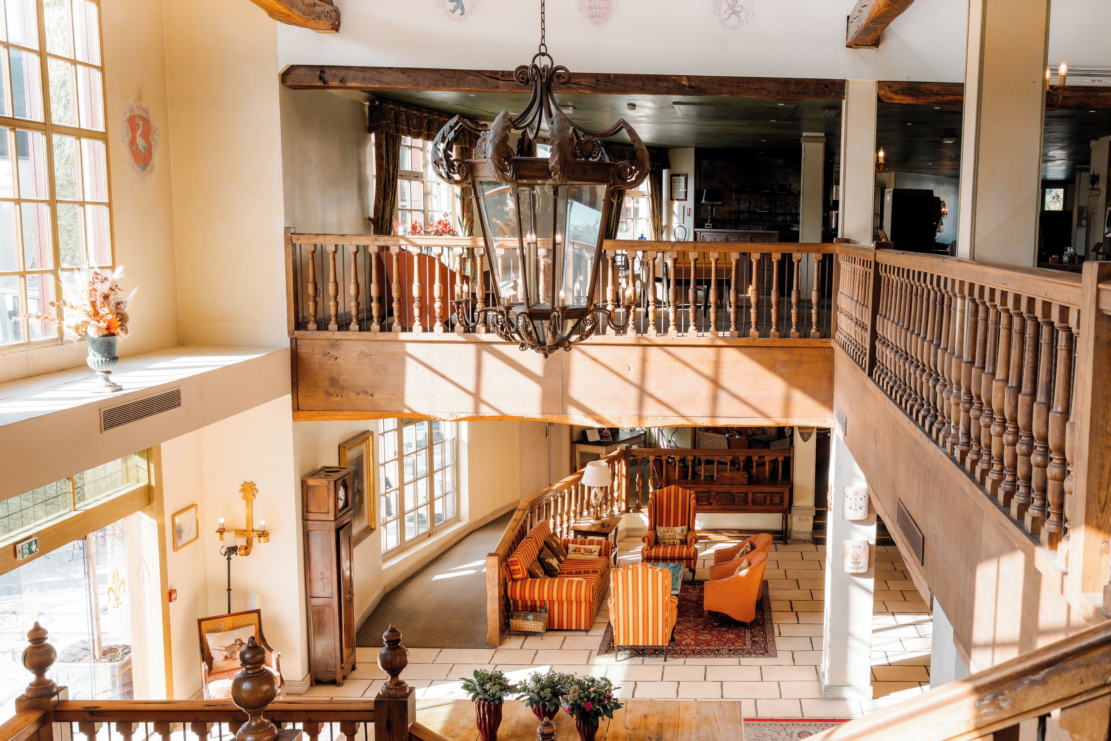 A spacious interior with a high ceiling, wooden beams, and a grand staircase leading to an upper level.