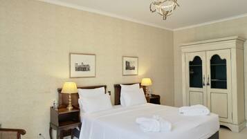 Een hotelkamer met een groot bed, twee nachtkastjes met lampen, een kledingkast en ingelijste foto's aan de muur.