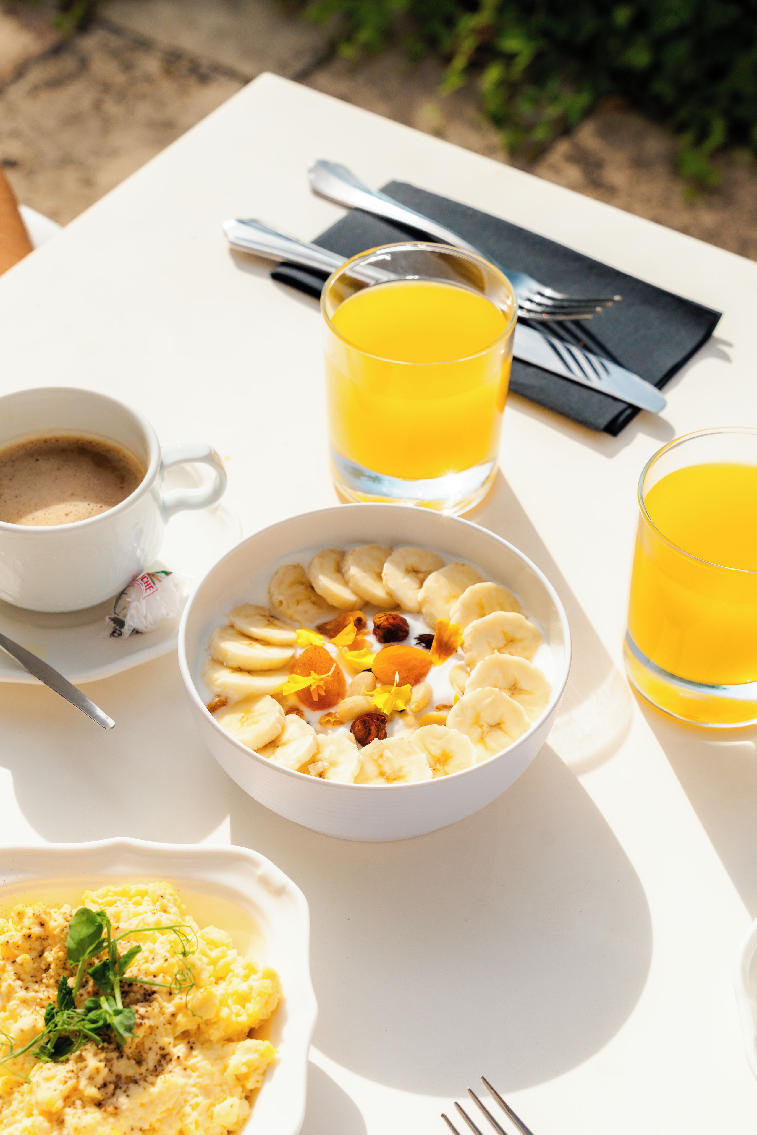 Une table avec un bol de nourriture, une tasse de café et deux verres de jus d’orange.