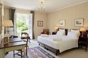 Une chambre d’hôtel avec un grand lit, des tables de chevet avec des lampes, un bureau, une chaise et une vue sur l’extérieur.