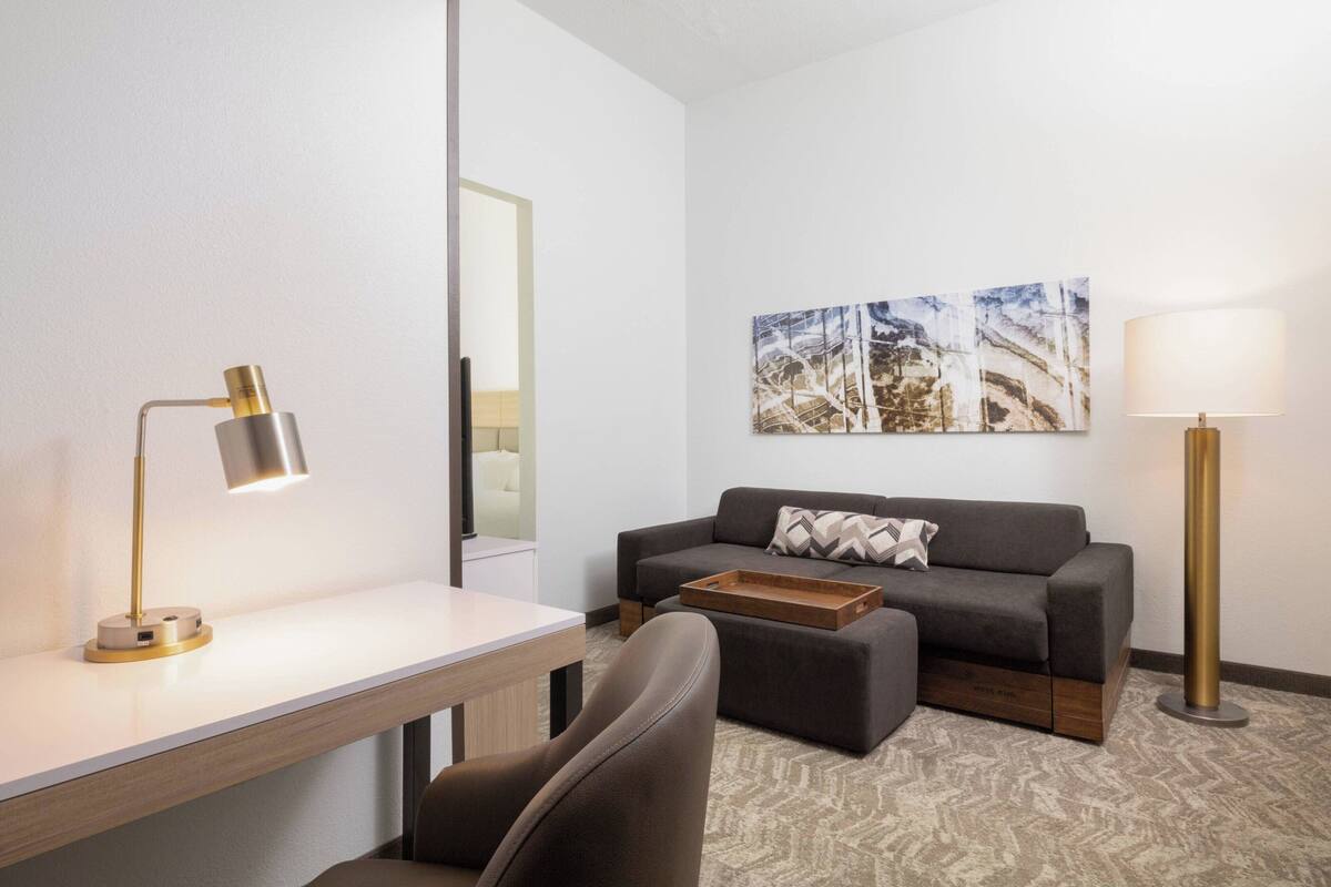 A modern living room with a sofa, a coffee table, a desk, and a lamp.