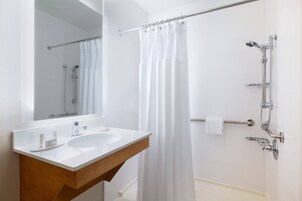 Un baño con lavamanos, espejo y ducha blancos.