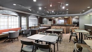 A modern restaurant with round tables and booths, large windows, and a bar area. - Springhill Suites by Marriott Williamsburg (Williamsburg)