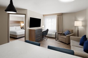 Ein Hotelzimmer mit Bett, Schreibtisch, Fernseher und einer Sitzecke.