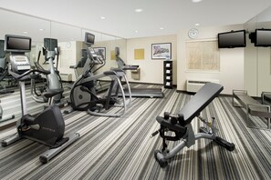 Ein Fitnessraum eines Hotels mit unterschiedlichen Trainingsgeräten, darunter Laufbänder, Ergometer und Kraftgeräte.