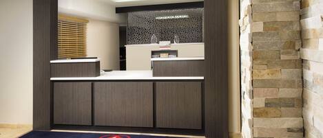A reception area with a reception desk, a decorative wall, and a stone wall on the right.