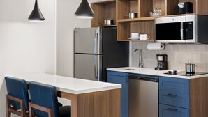 A modern kitchen with a stainless steel refrigerator, a built-in microwave, a coffee maker, and a dishwasher.