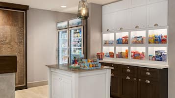 A kitchen with a central island, white cabinets, and a snack display.