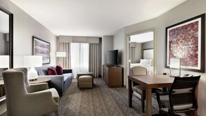 Une chambre d’hôtel avec un lit, un bureau, une chaise, une télévision et une grande fenêtre avec des rideaux.