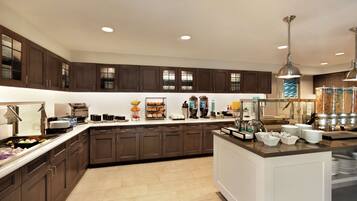 Una cocina moderna con armarios de madera oscura, una isla central y diversos productos para el desayuno.