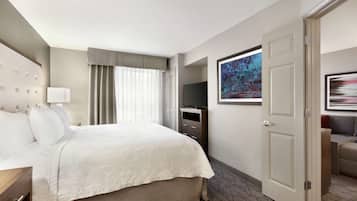 A hotel room with a large bed, a television, a desk, and a door.