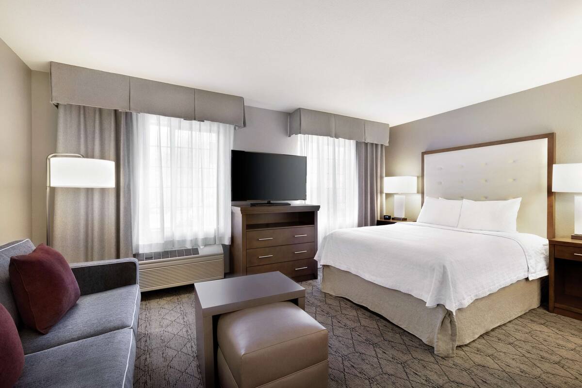A hotel room with a bed, a TV, a desk, and a couch.