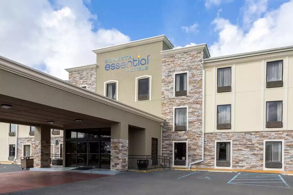 A Sonesta Essential Hotel with a stone facade, multiple windows, and a covered entrance.
