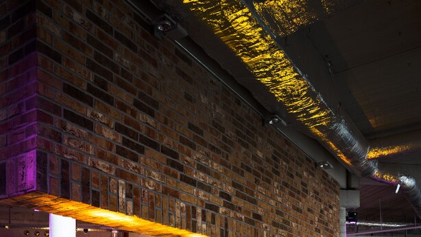Pared de ladrillo con chimenea, mesas y sillas de madera en un restaurante.