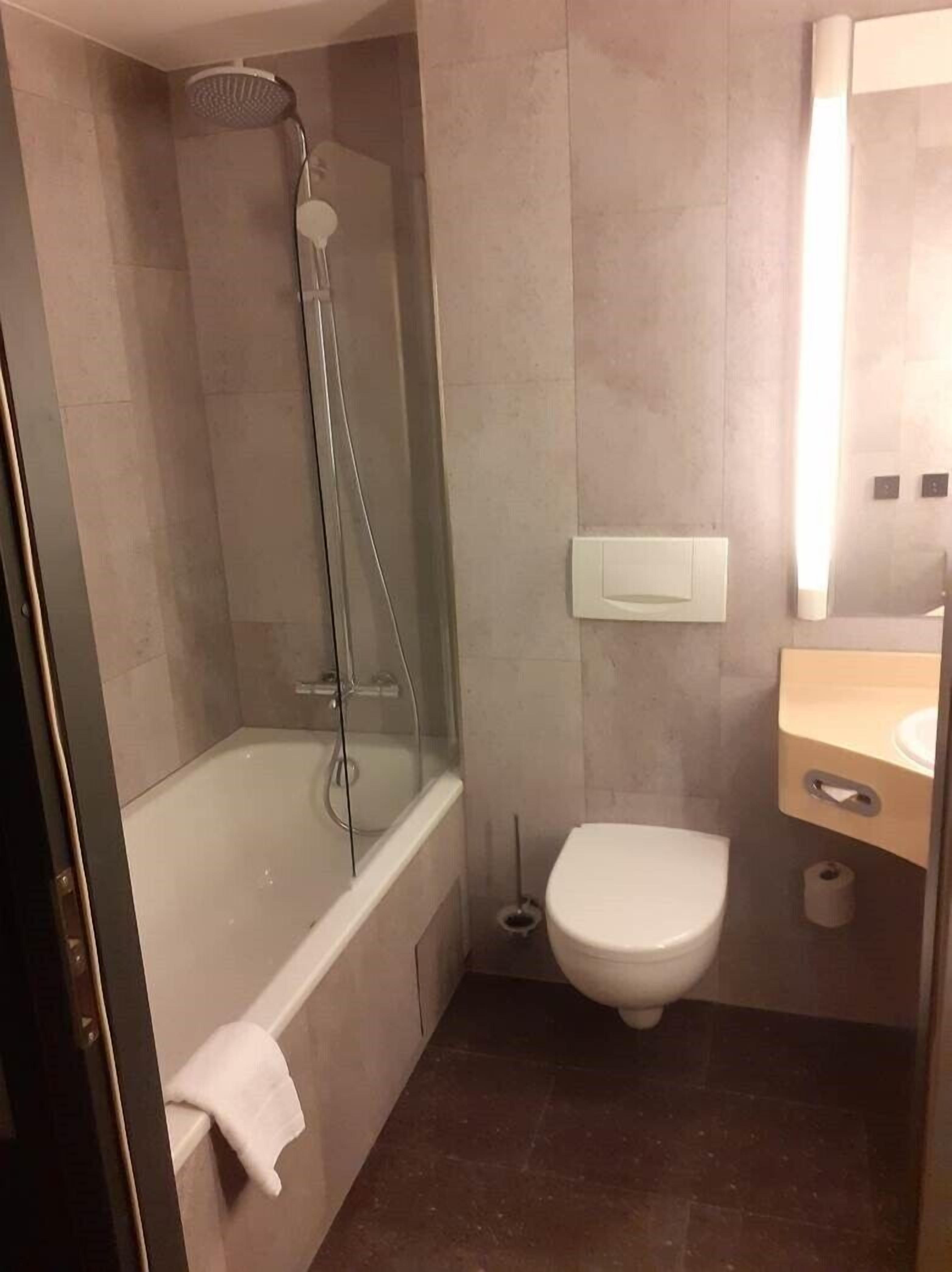 A bathroom with a glass-enclosed shower, a bathtub, a toilet, and a sink with a mirror.