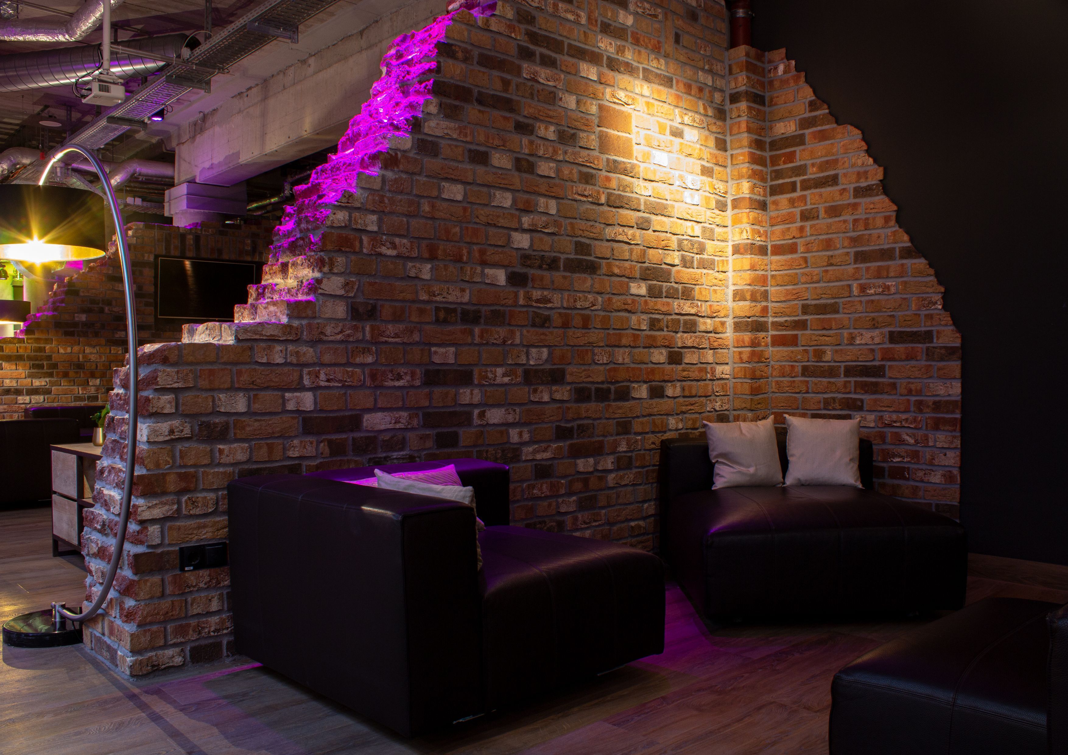 A cozy lounge area with a brick wall, a curved ceiling, and a modern sofa.