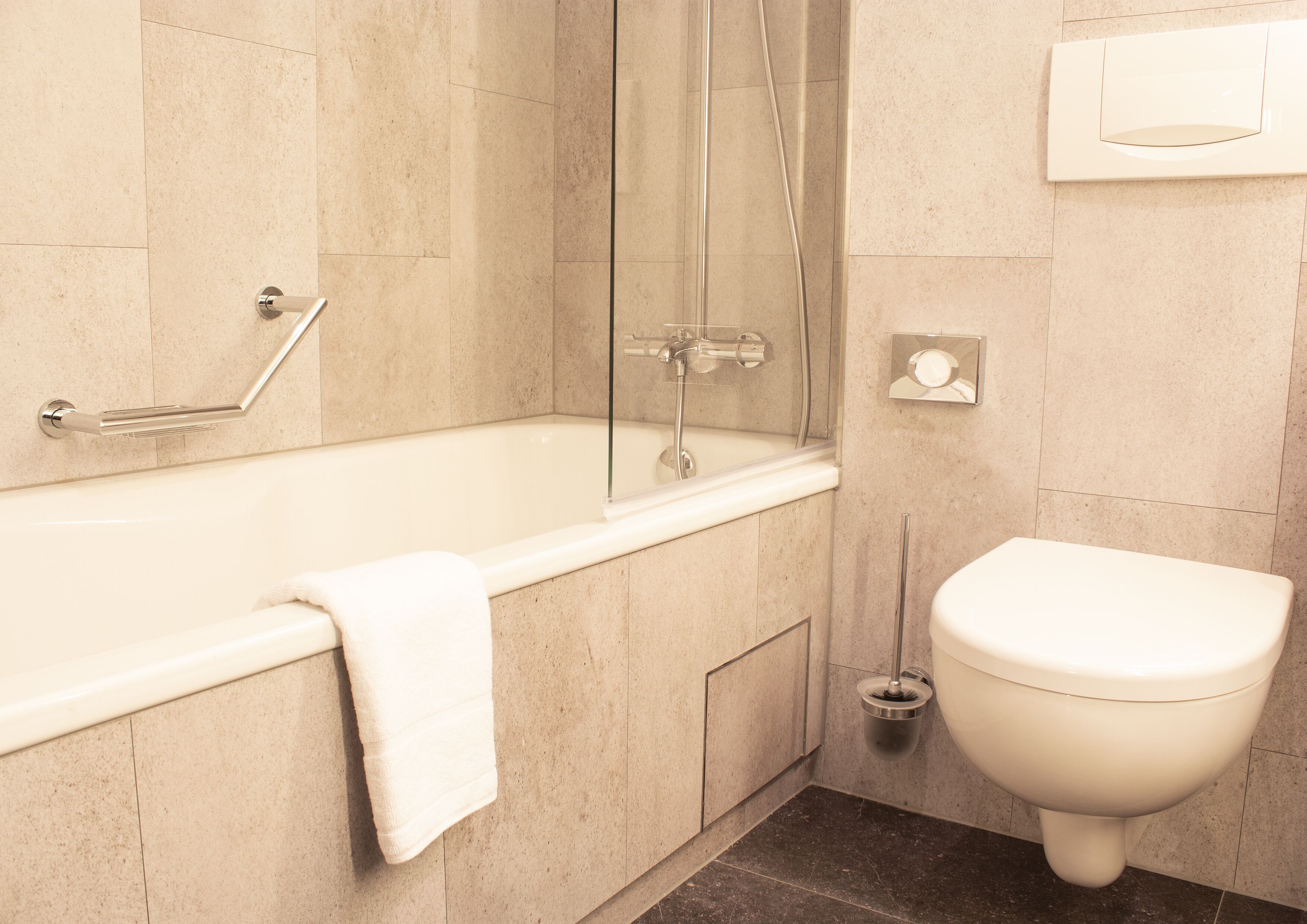 A modern bathroom with a bathtub, toilet, and shower.